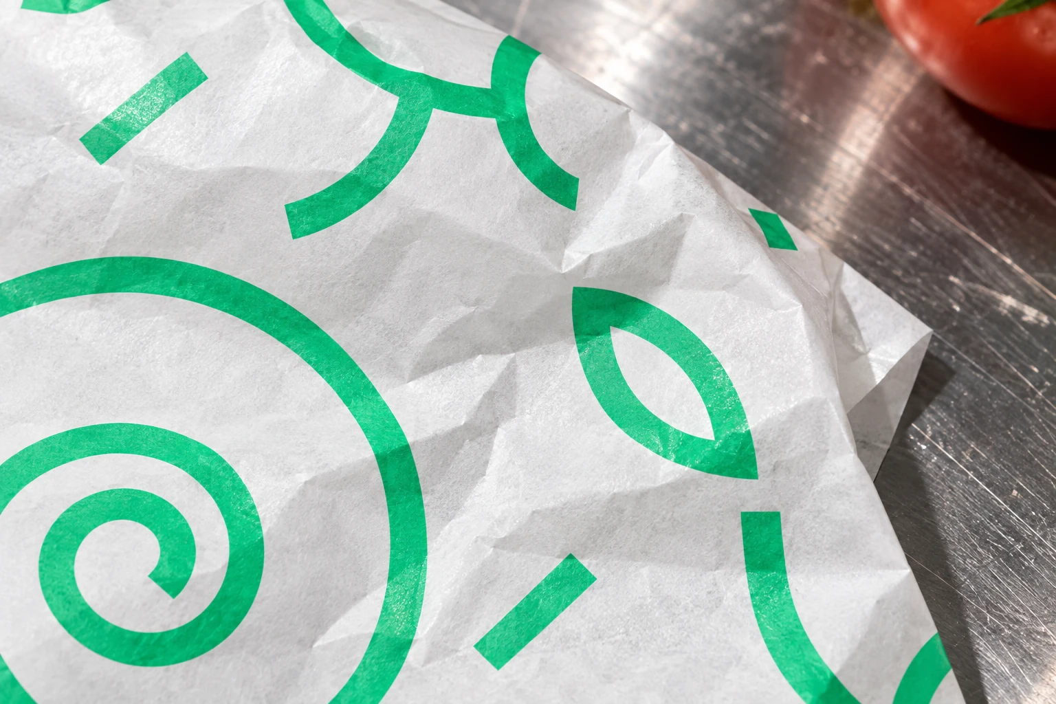 Dettaglio del pattern verde stampato sulla carta piegata, appoggiata sull’acciaio